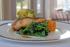 seafood dish with spinach rice and fruit garnish