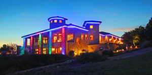 two story home with colored light accents at dusk