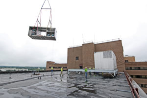 crane lifting HVAC equipment onto roof