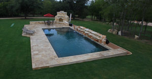 backyard pool in wooded yard with outdoor fireplace