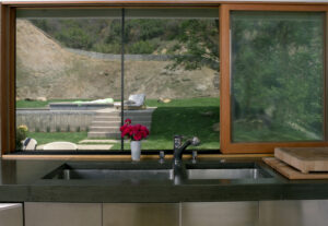 stained concrete kitchen counter with window overlooking backyard